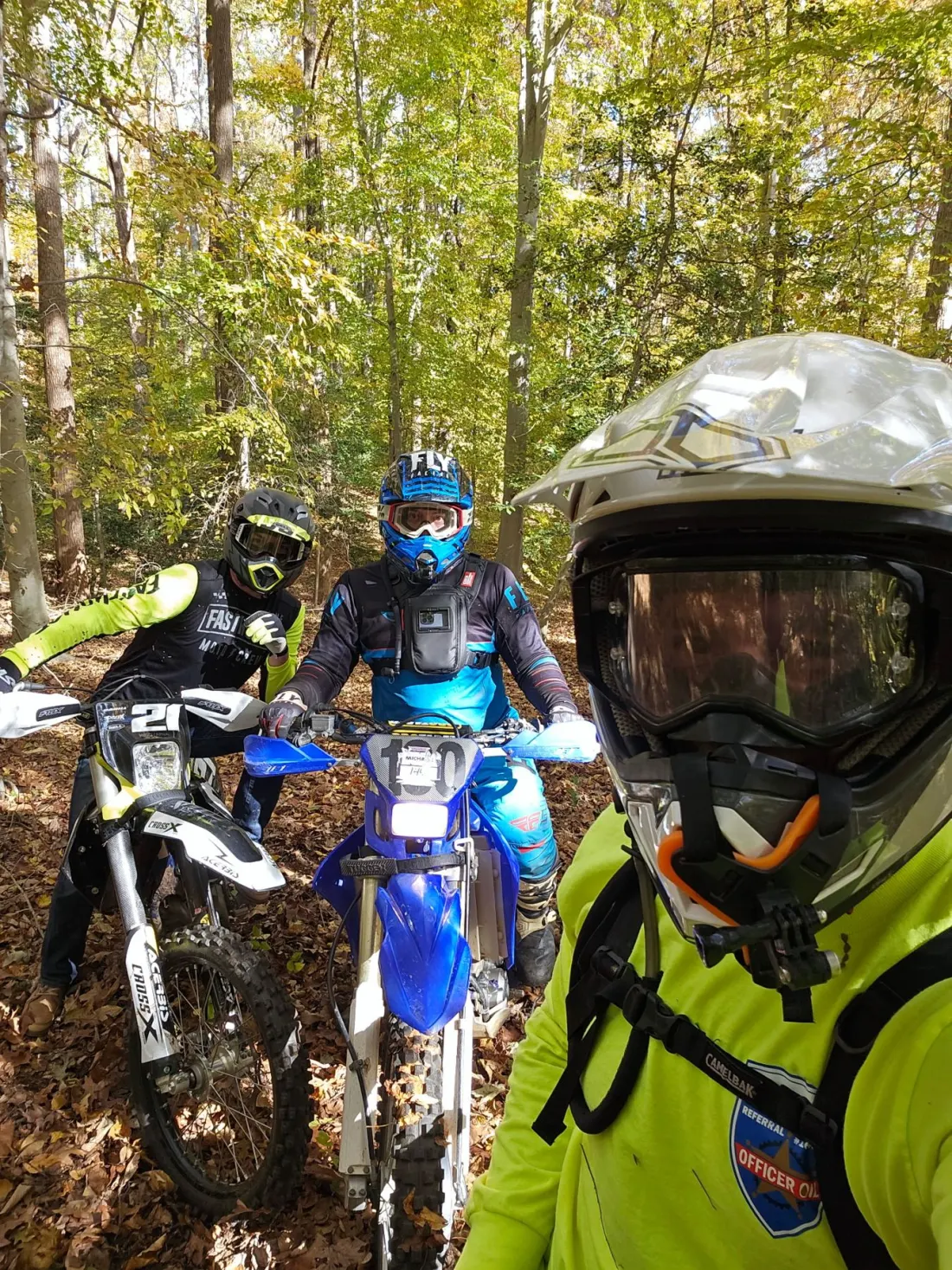 Three riders stopped on a leafy single-track trail in the woods